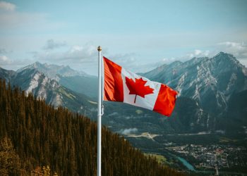 Canadian flag with mountain and small town views in summer